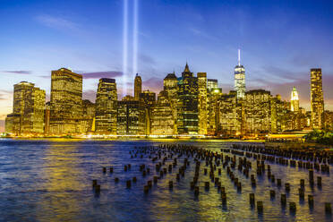 Wolkenkratzer in Lower Manhattan einschließlich des One World Trade Center von der anderen Seite des East River bei Nacht, mit Lichtstrahlen vom Tribute in Light 9/11 Memorial, New York City, New York, Vereinigte Staaten von Amerika, Nordamerika - RHPLF01098