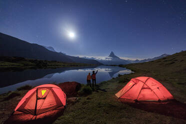 Wanderer bewundern das Matterhorn, das sich im Stellisee spiegelt, in einer sternenklaren Vollmondnacht, Zermatt, Kanton Wallis, Schweizer Alpen, Schweiz, Europa - RHPLF01184