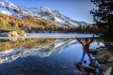 Wanderer erfreut sich an der farbenfrohen Herbstlandschaft rund um den Saoseo See, Poschiavo Tal, Kanton Graubünden, Schweiz, Europa - RHPLF01188