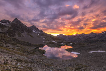 Fiery sky at dawn reflected in Lai Ghiacciato framed by peaks, Val Ursaregls, Chiavenna Valley, Valtellina, Lombardy, Italy, Europe - RHPLF01202