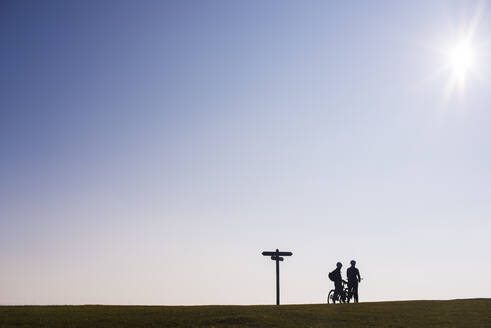 Radfahrer machen bei Sonnenuntergang eine Pause auf einem Hügel in Dorset, England, Vereinigtes Königreich, Europa - RHPLF01244