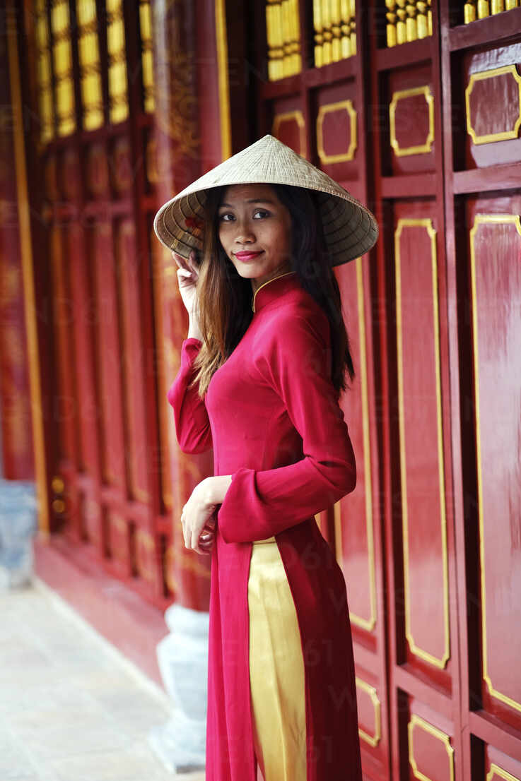 Vietnamese woman in traditional Ao dai dress and Non la conical