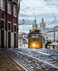 Romantische Atmosphäre in den alten Straßen von Alfama mit der Burg im Hintergrund und der Straßenbahnlinie 28, Lissabon, Portugal, Europa - RHPLF01385