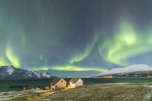 Das Nordlicht (Aurora Borealis) und die Sterne beleuchten die Holzhäuser namens Rorbu am Meer, Djupvik, Lyngen Alps, Troms, Norwegen, Skandinavien, Europa - RHPLF01416