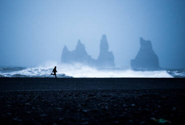 Tourist running on Black Sand Beach, Iceland, Polar Regions - RHPLF01446