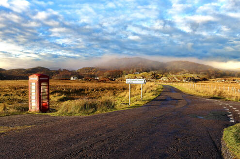 Herbstansicht einer roten Telefonzelle am Rande einer ruhigen Straße in den abgelegenen nebligen Ardnamurchan-Mooren der schottischen Highlands, Schottland, Vereinigtes Königreich, Europa - RHPLF01486