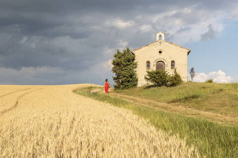 Frau in rotem Kleid und Weidenkorb, vorbei an der Kapelle Notre-Dame-de-Sante, Entrevennes, Alpes-de-Haute-Provence, Provence-Alpes Cote d'Azur, Frankreich, Europa, lizenzfreies Stockfoto