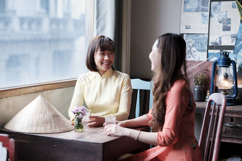 Zwei Freunde in Ao Dai-Kleidern trinken Kaffee in einem Saigoner Kaffeehaus, Ho-Chi-Minh-Stadt, Vietnam, Indochina, Südostasien, Asien - RHPLF01622