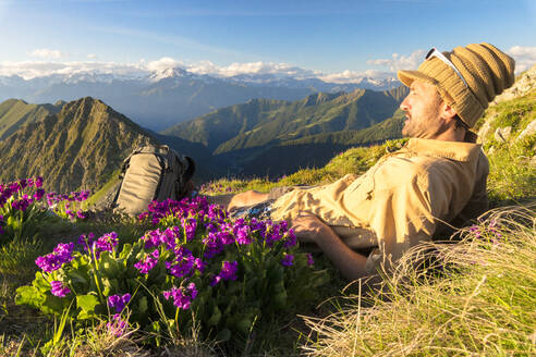 Mann liegt auf dem Gipfel des Monte Azzarini und schaut auf den Monte Disgrazia und den Monte Pedena, Albaredo-Tal, Orobie-Alpen, Lombardei, Italien, Europa - RHPLF01642