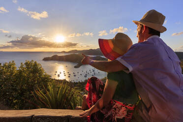 Paar blickt von Shirley Heights bei Sonnenuntergang auf English Harbour, Antigua, Antigua und Barbuda, Leeward-Inseln, Westindien, Karibik, Mittelamerika - RHPLF01649