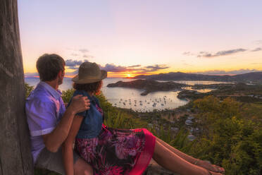 Paar blickt von Shirley Heights bei Sonnenuntergang über English Harbour, Antigua, Antigua und Barbuda, Leeward-Inseln, Westindien, Karibik, Mittelamerika - RHPLF01650