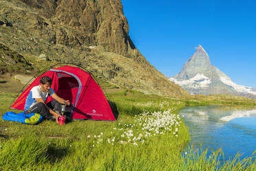 Wanderer am Riffelsee macht Kaffee vor dem Zelt mit Blick auf das Matterhorn, Zermatt, Kanton Wallis, Schweizer Alpen, Schweiz, Europa - RHPLF01651