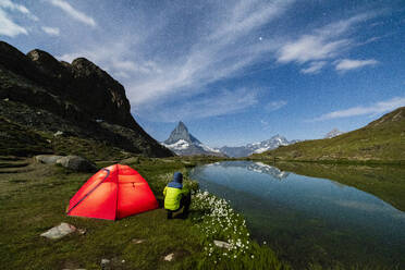 Hiker beside tent looking towards the Matterhorn from lake Riffelsee, Zermatt, canton of Valais, Swiss Alps, Switzerland, Europe - RHPLF01652