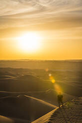 Mann genießt den Sonnenuntergang in den riesigen Sanddünen der Wüste Sahara, Timimoun, Westalgerien, Nordafrika, Afrika - RHPLF01655