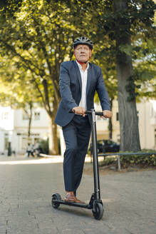 Senior man riding e-scooter in the city - GUSF02380