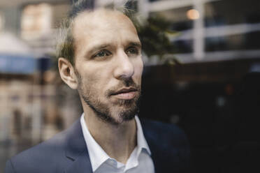 Portrait of businessman looking out of window - GUSF02385