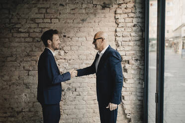 Senior and mid-adult businessman shaking hands - GUSF02401