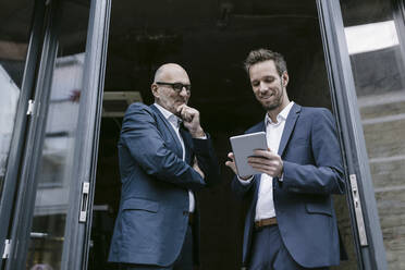 Smiling senior and mid-adult businessman with tablet having a meeting - GUSF02415