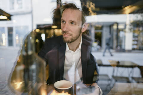 Porträt eines Geschäftsmannes in einem Café mit Blick aus dem Fenster, lizenzfreies Stockfoto