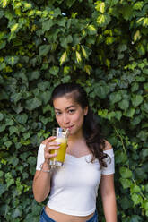 Porträt einer lächelnden jungen Frau, die ein gesundes Getränk trinkt - MGIF00684