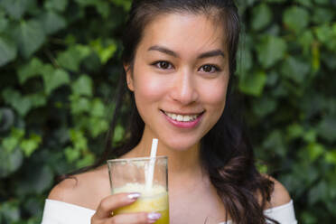 Porträt einer lächelnden jungen Frau, die ein gesundes Getränk hält - MGIF00685