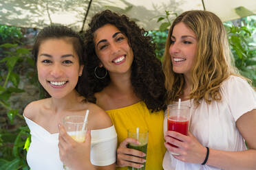 Portrait of three happy young women holding healthy drinks - MGIF00687