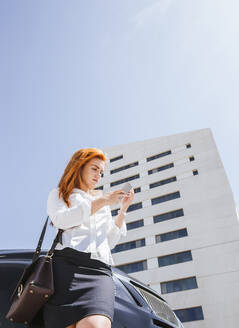 Geschäftsfrau mit Smartphone vor einem Geschäftsgebäude - LJF00700