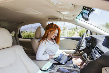 Business woman using laptop in a car - LJF00710