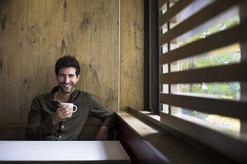 Porträt eines lachenden Mannes beim Kaffeetrinken in einem Café, lizenzfreies Stockfoto