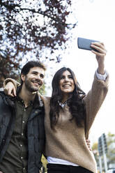 Porträt eines glücklichen Paares, das ein Selfie mit einem Mobiltelefon macht - ABZF02435