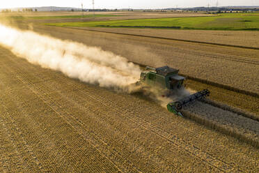 Aerial view of combine harvester on agricultural field during sunset - AMF07276