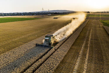 Luftaufnahme eines Mähdreschers auf einem landwirtschaftlichen Feld gegen den klaren Himmel bei Sonnenuntergang - AMF07279