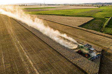 Aerial view of combine harvester on agricultural field during sunset - AMF07280