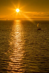 Sailing boat and sunset over Elliott Bay with Bainbridge Island visible on the horizon viewed from Bell Harbour Marina, Seattle, Washington State, United States of America, North America - RHPLF01979