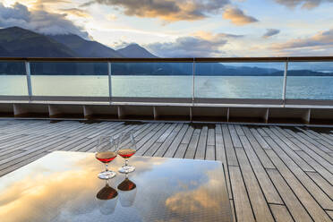 Glühende Cognac (Brandy) Reflexionen, Glastisch bei Sonnenuntergang, Kreuzfahrtschiff Heck, Resurrection Bay, Kenai Halbinsel, Alaska, Vereinigte Staaten von Amerika, Nordamerika - RHPLF02407