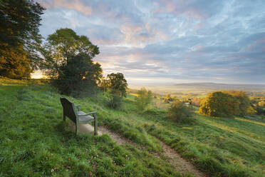 Cotswold Way Pfad und Bank mit Blick auf die Malvern Hills bei Sonnenuntergang, Ford, Cotswolds, Gloucestershire, England, Vereinigtes Königreich, Europa - RHPLF02854