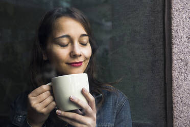 Junge Frau in einem Café mit einer Tasse Kaffee und geschlossenen Augen - ABZF02479