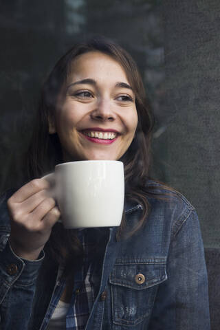 Junge Frau in einem Café mit einer Tasse Kaffee und Blick zur Seite, lizenzfreies Stockfoto