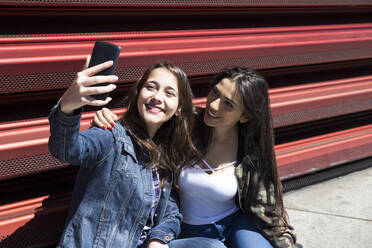 Young women sitting on ground and posing for selfie in Madrid, Spain - ABZF02495