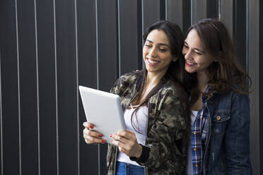 Smiling friends using tablet, taking a selfie - ABZF02502