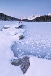 Man standing on the shore of frozen lake, Lej da Staz, St. Moritz, Engadine, Canton of Graubunden (Grisons), Switzerland, Europe - RHPLF03241