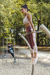 Woman lifting herself up on a fitness trail - MFF04784