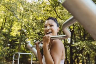 Glückliche Frau, die sich auf einem Fitnessparcours aufrichtet - MFF04786