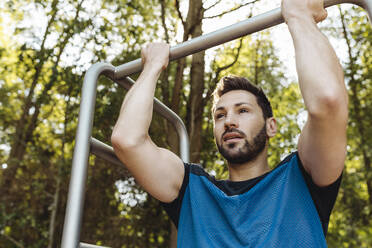 Mann hebt sich auf einem Fitnessparcours hoch - MFF04794