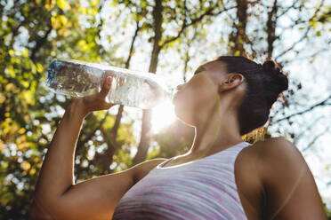 Frau trinkt in der Sonne Wasser aus einer Plastikflasche - MFF04809