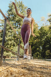 Frau balanciert auf einem Seil auf einem Fitnessparcours - MFF04815