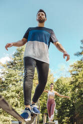 Mann balanciert auf Slackline auf einem Fitnessparcours - MFF04818