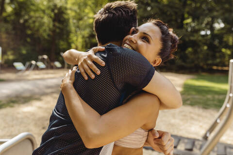 Mann und Frau umarmen sich auf einem Fitnessparcours, lizenzfreies Stockfoto