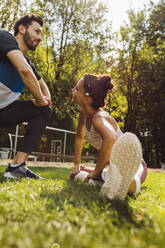 Man and woman stretching on grass near a fitness trail - MFF04839
