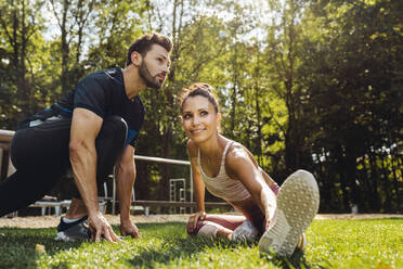 Man and woman stretching on grass near a fitness trail - MFF04842